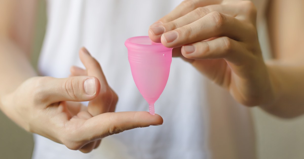 Frau hält Menstruationstasse in den Händen