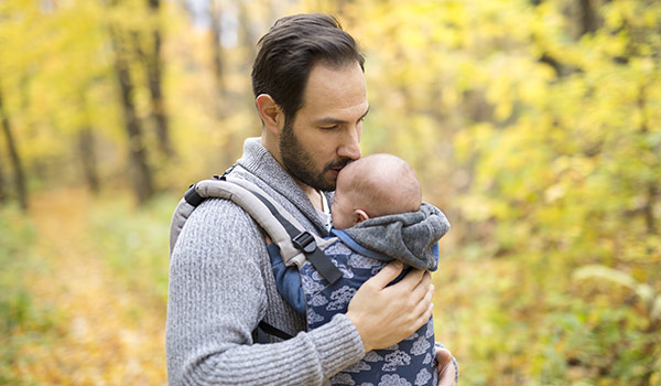 Vater trägt ein Baby in der Trage im Wald